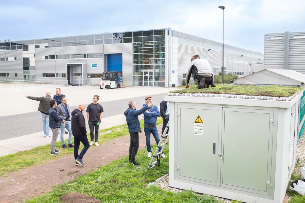 Groep mensen bij groen elektriciteitshuisje, duurzaamheidsproject