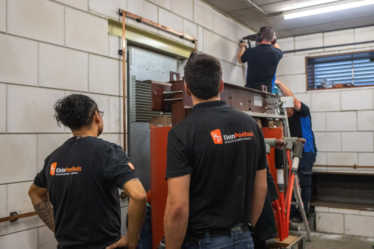KleinPoelhuis technici installeren HVAC-apparatuur in industriële ruimte met witte tegelmuren