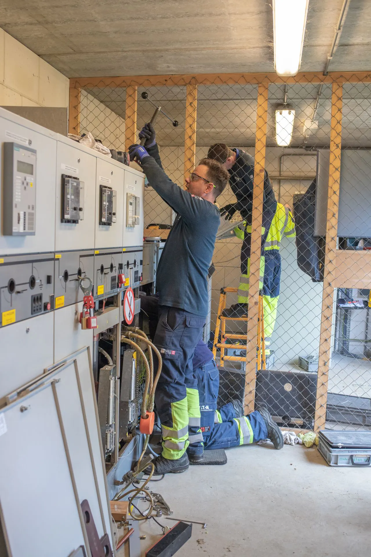 Elektriciens werken aan elektrische installatie in industriële ruimte met aan bedieningspanelen cleantech campus