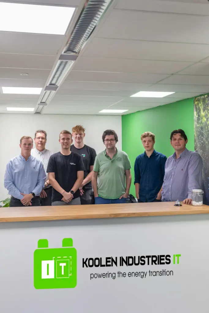 Koolen Industries IT team posing together in modern office with green accent wall - powering energy transition