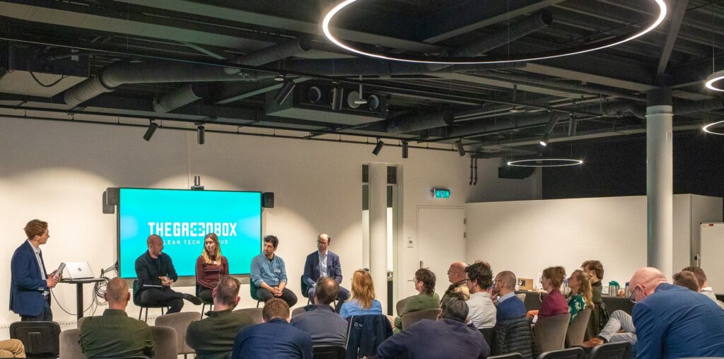 Panel discussie bij The Green Box Clean Tech Hub met sprekers en publiek in moderne vergaderruimte