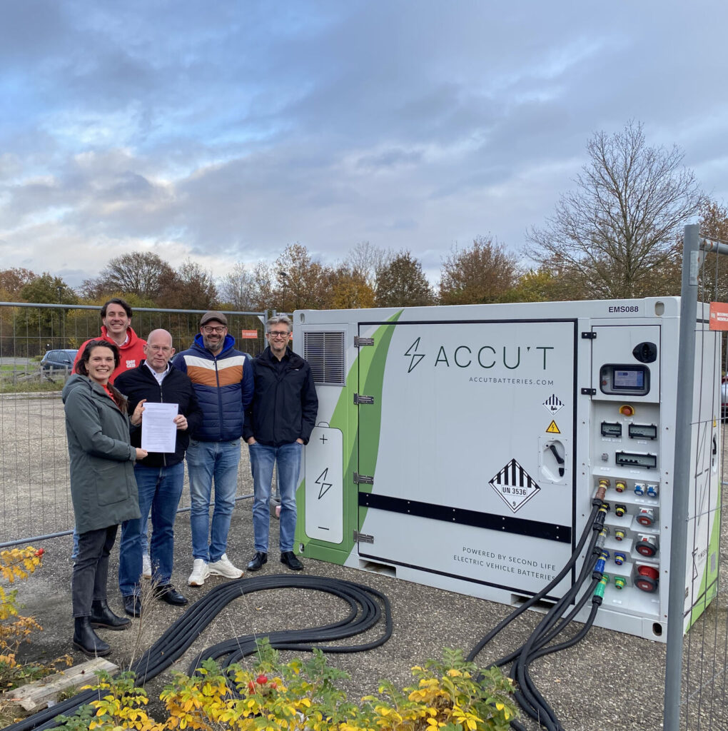 Groep mensen staat bij ACCU'T mobiele batterij-oplader voor elektrische voertuigen op buitenlocatie