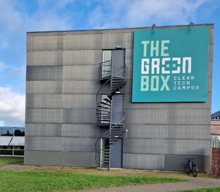 The Green Box Clean Tech Campus building met grijze gevel en spiraalvormige buitentrap tegen blauwe hemel