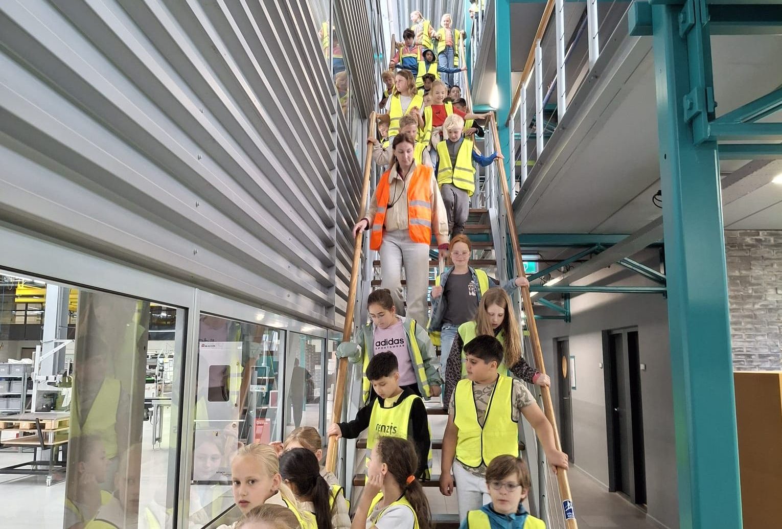 Groep kinderen in gele veiligheidshesjes loopt trap af tijdens schoolexcursie op The Green Box