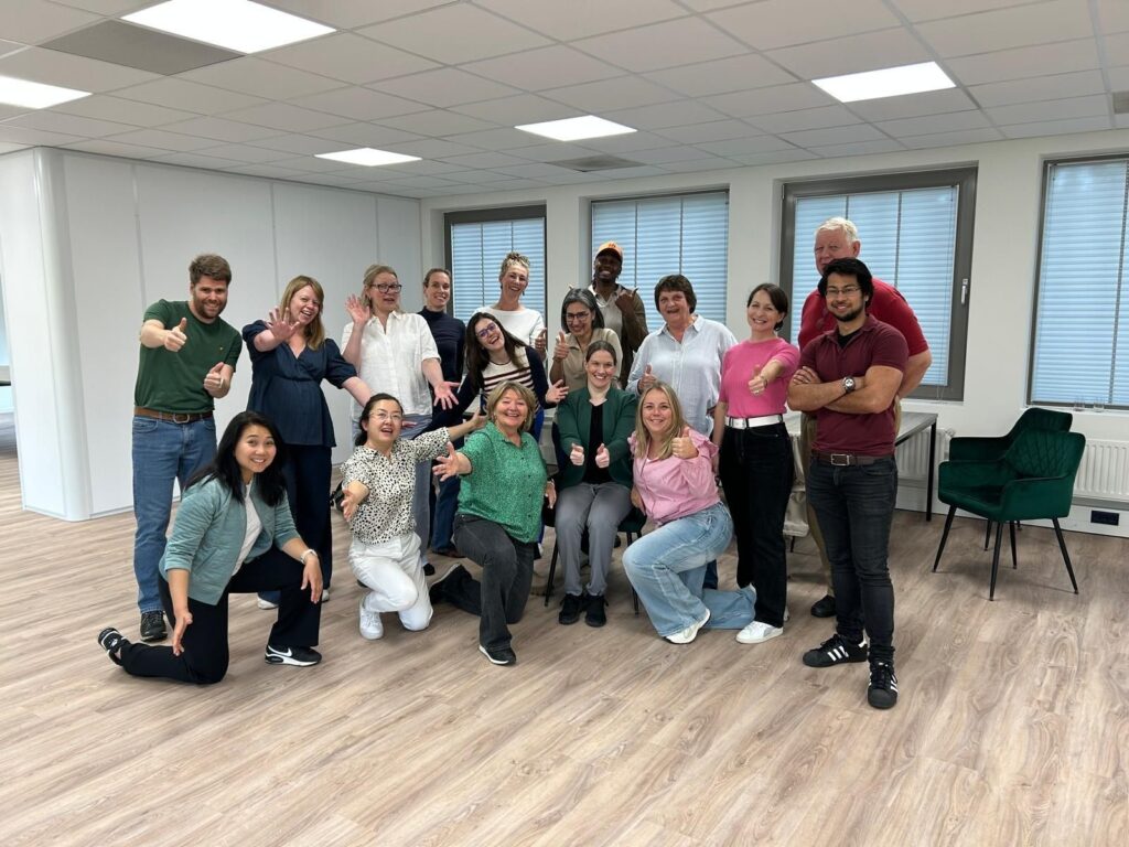 Groepsfoto van een divers team van collega's die poseren in een moderne kantoorruimte tijdens een bedrijfsevenement.
