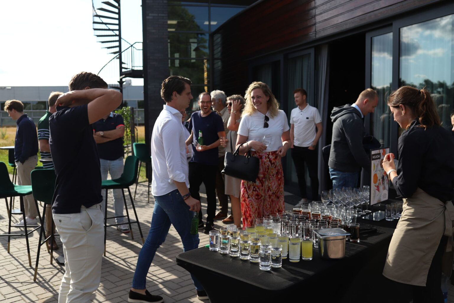Groep mensen op een zakelijk netwerkborrel op een terras met drankjes en glazen op een tafel