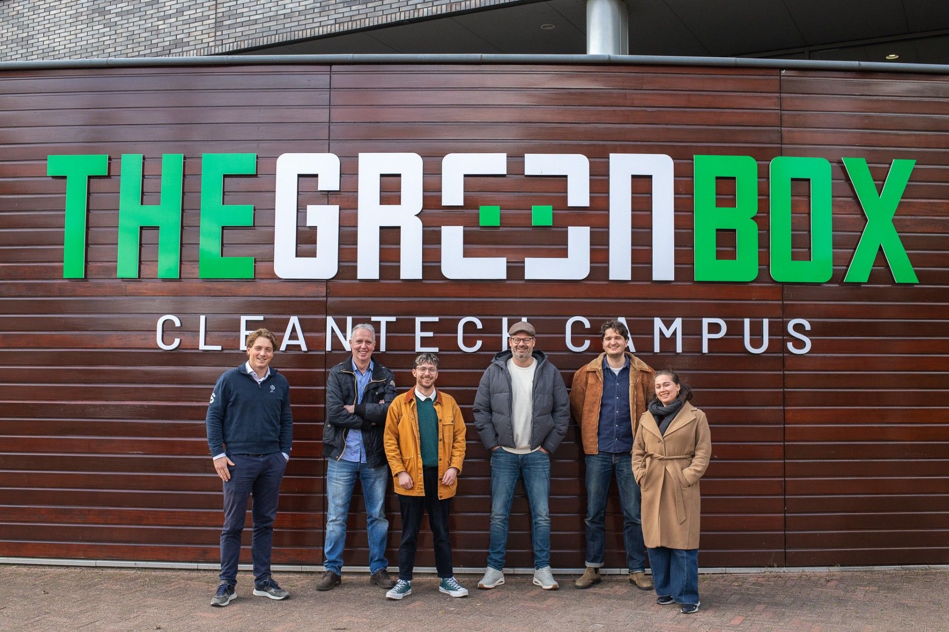 Zes professionals poseren voor het bord van The Green Box Cleantech Campus in Nederland.