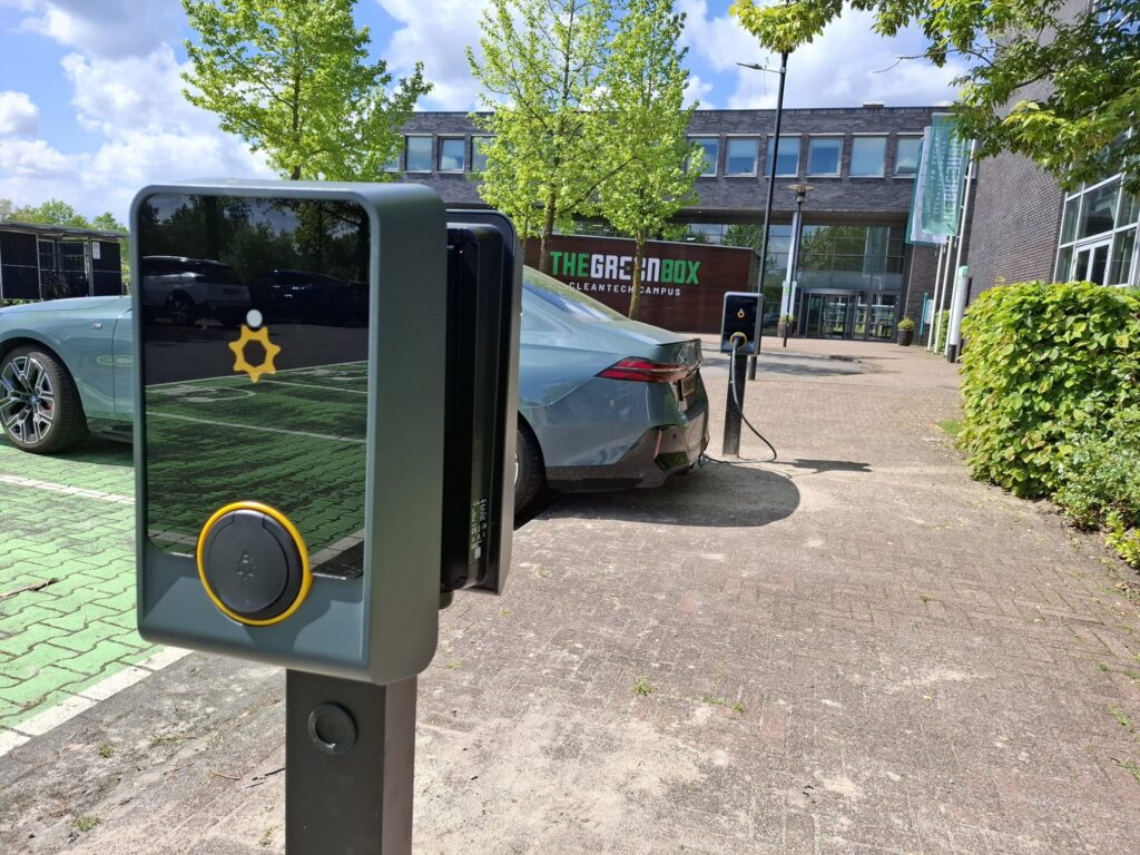 Elektrische auto's opladen bij The Green Box Cleantech Campus met moderne laadpalen op groene parkeerplaats.